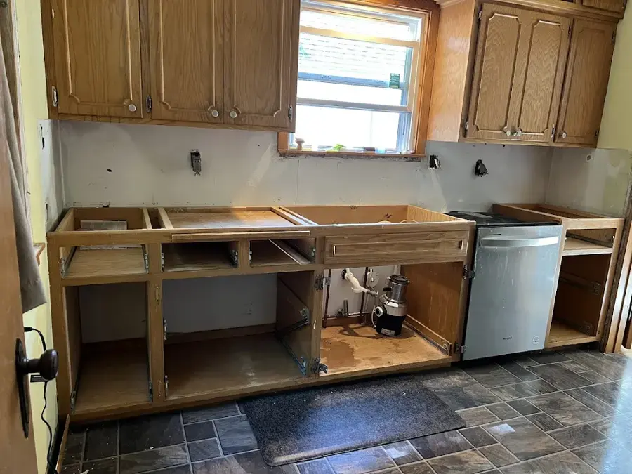 Kitchen base cabinets opened up beside the dishwasher after a leak under the sink