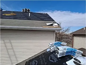 Roof with a section of shingles stripped and new shingle bundles staged during a repair